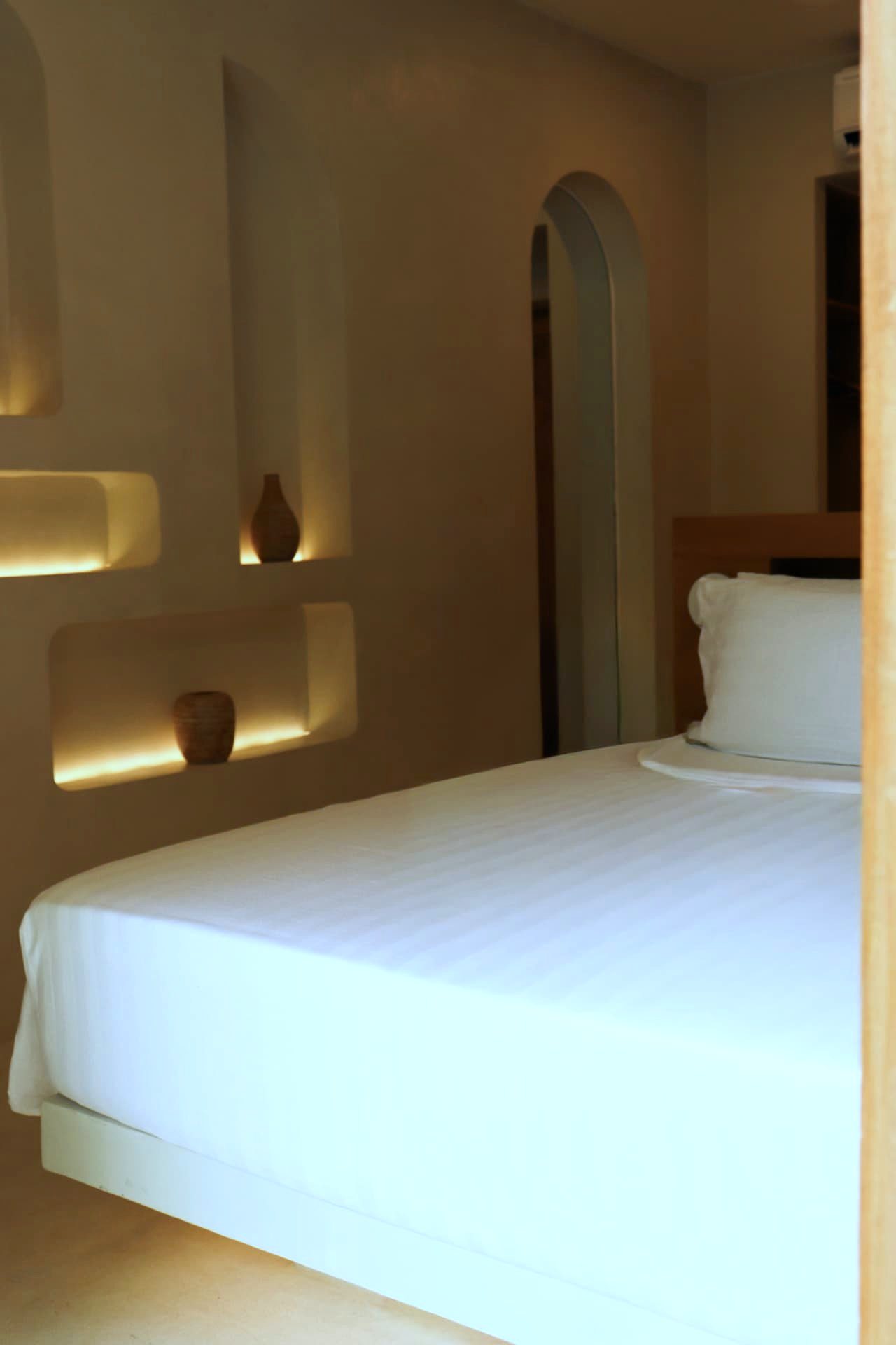 Backlit plaster shelving niches beside the bed
