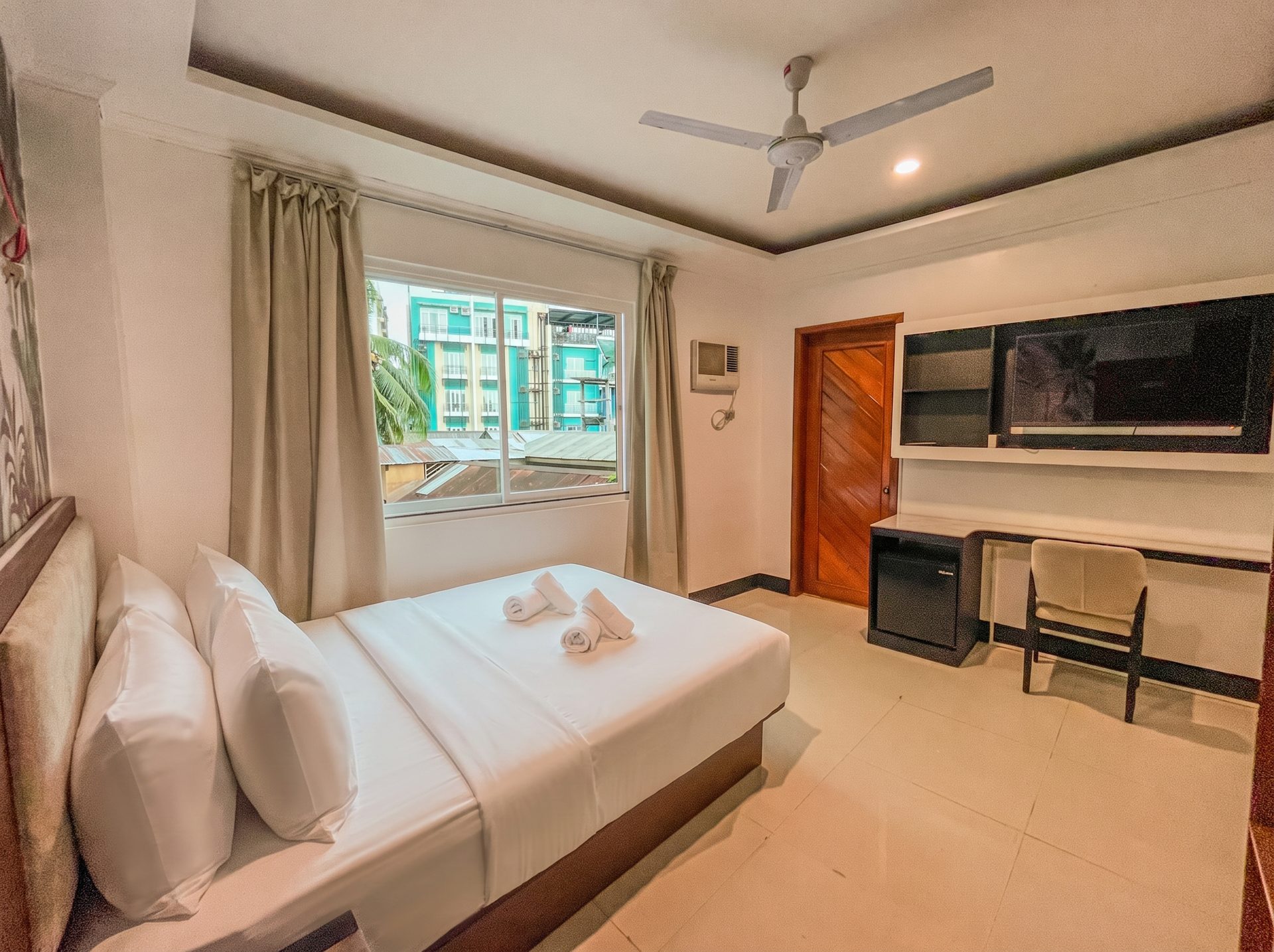 Room with large window, desk and TV at The Town