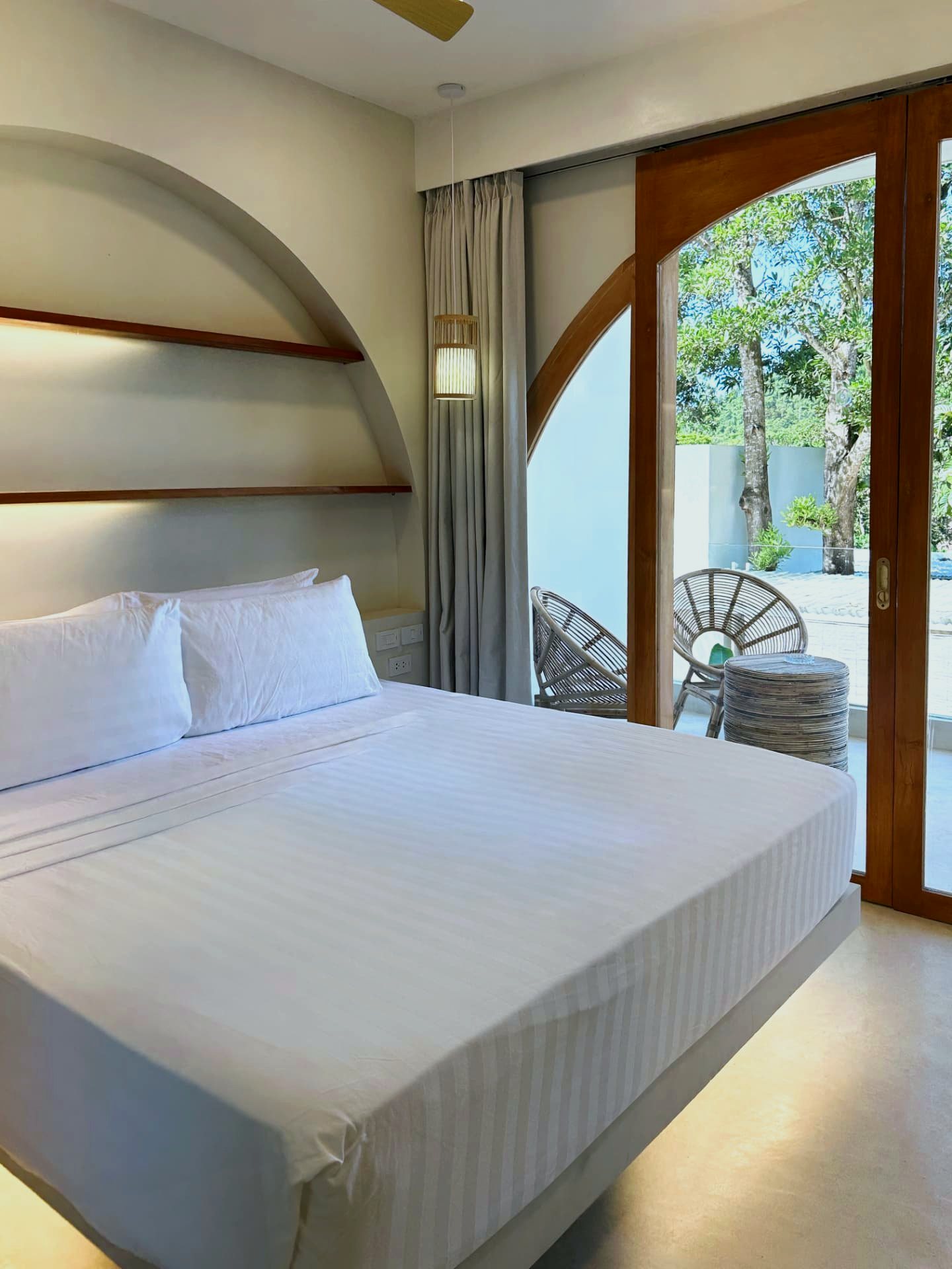 King bed beside sliding arched doors to the balcony