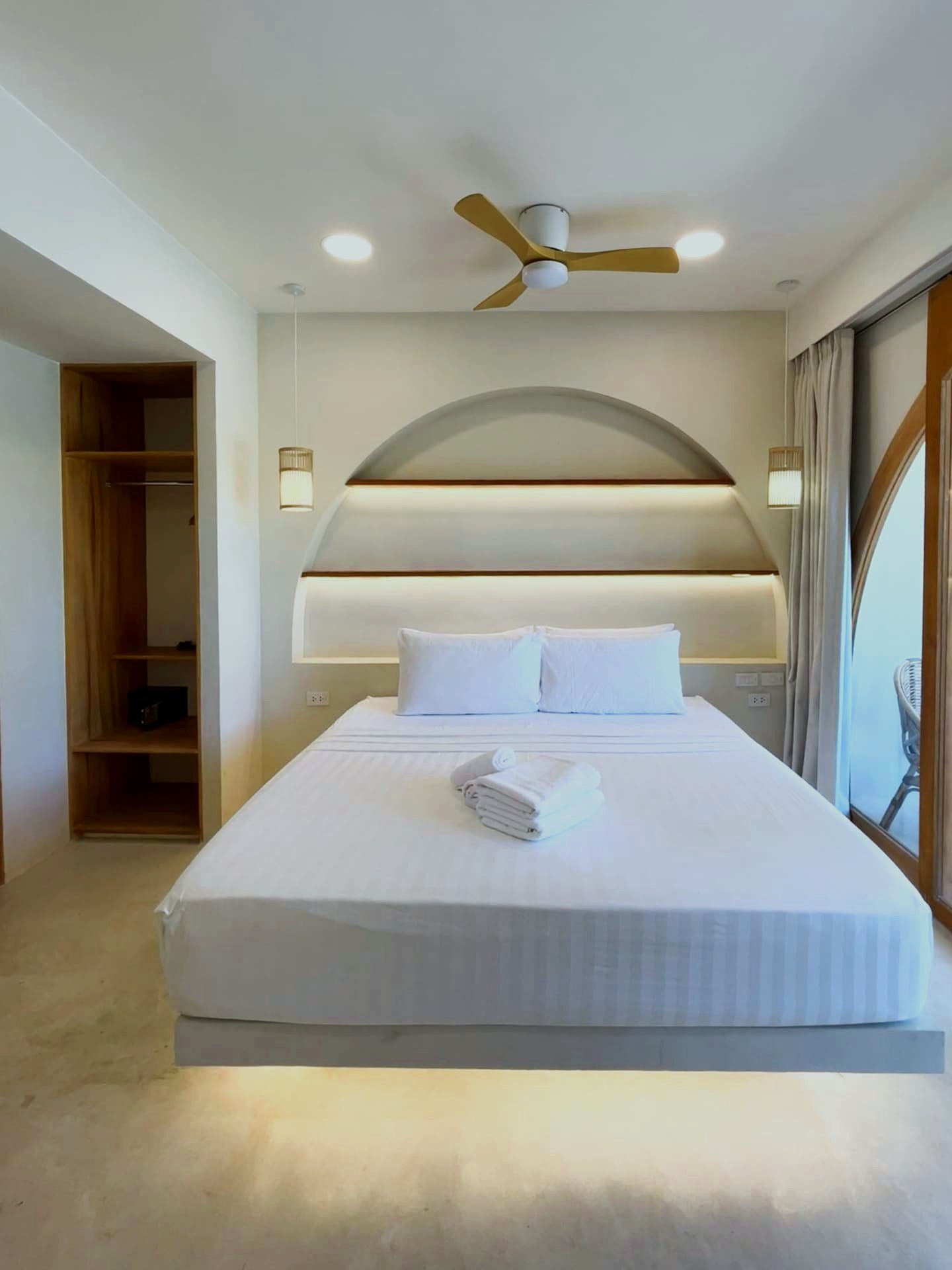 King bed with arched backlit headboard and rattan pendants