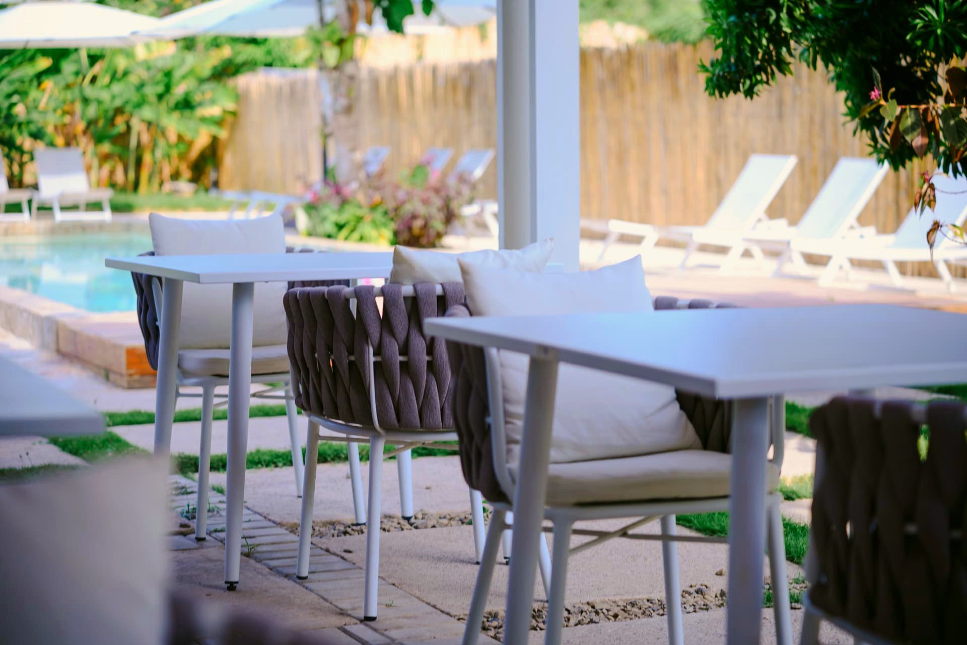 Restaurant tables with woven chairs beside the pool