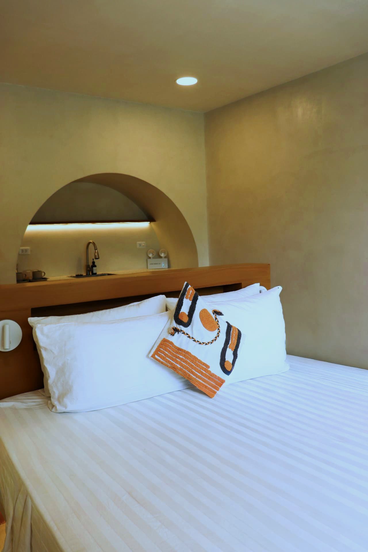 King bed with kitchenette arch behind the timber headboard