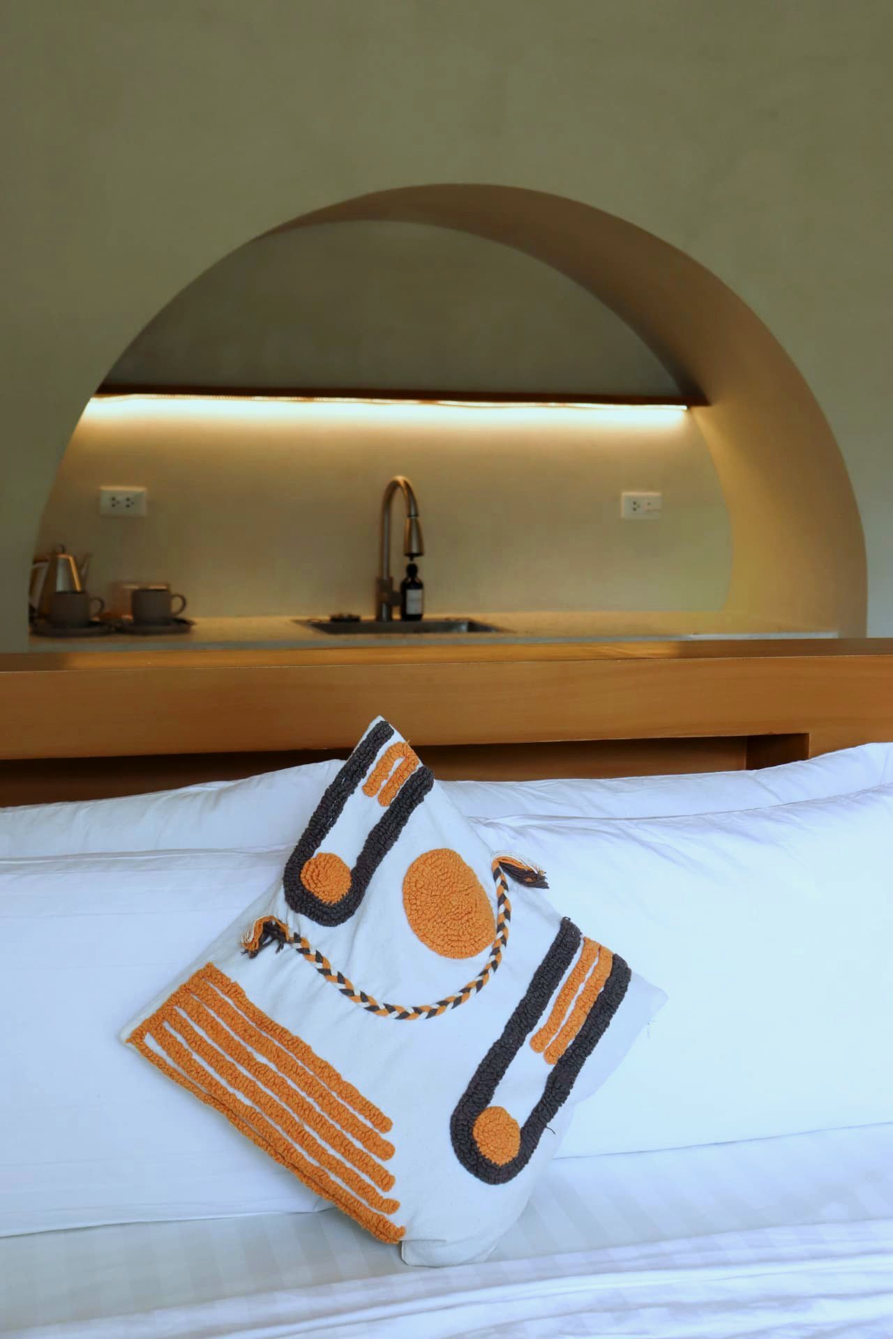 Cushion detail on the bed with kitchenette arch behind