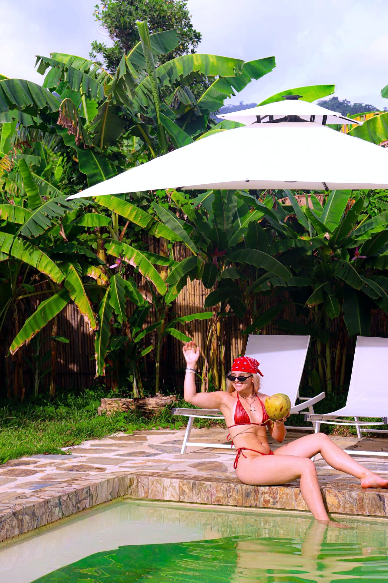 Guest relaxing at the pool edge under a parasol