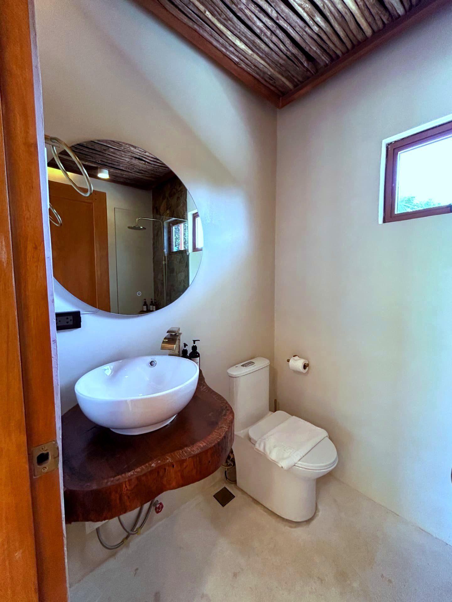 Bathroom with live-edge wood vanity, vessel basin and round mirror
