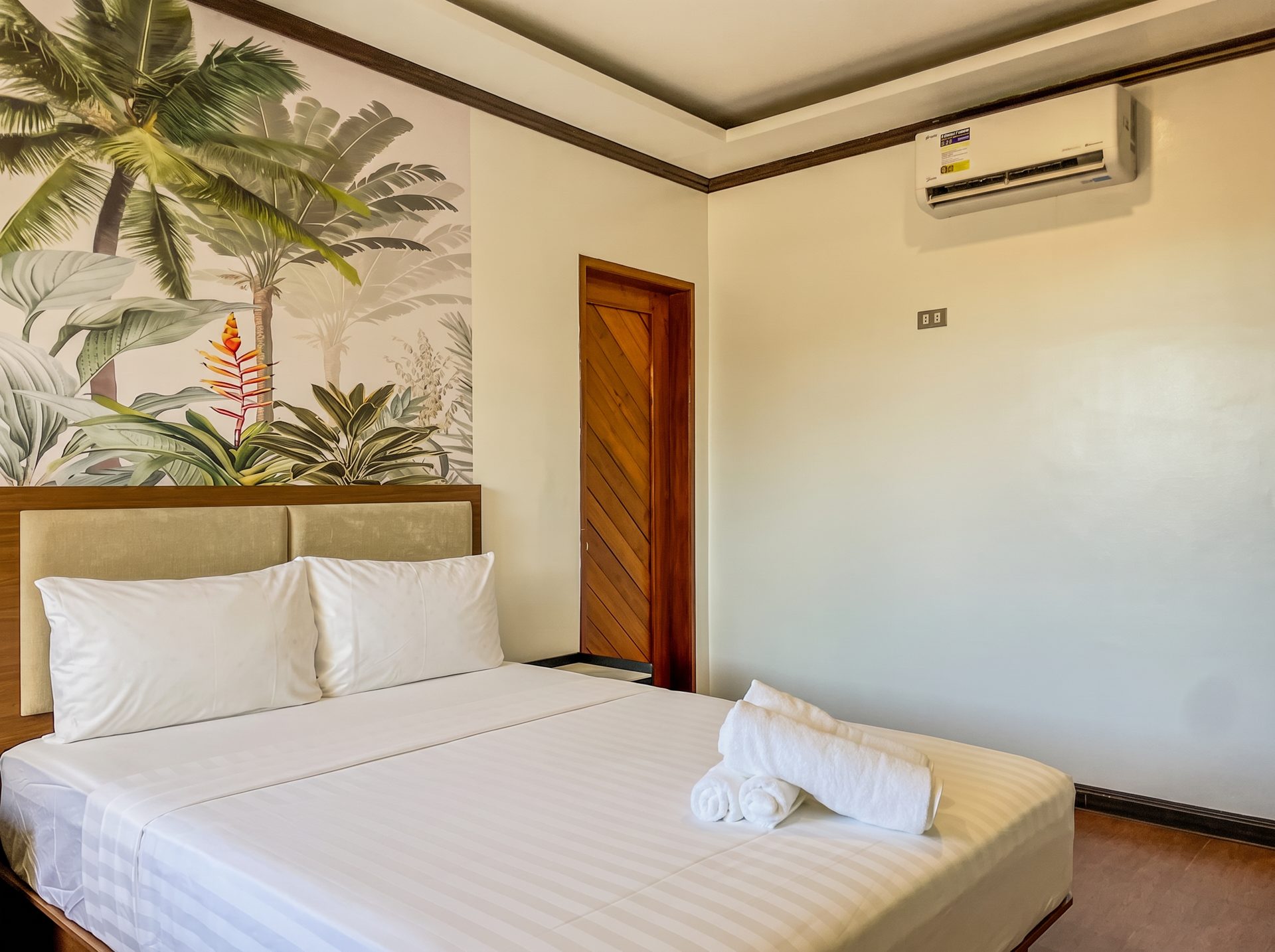 King bed with palm mural and air conditioning at The Town