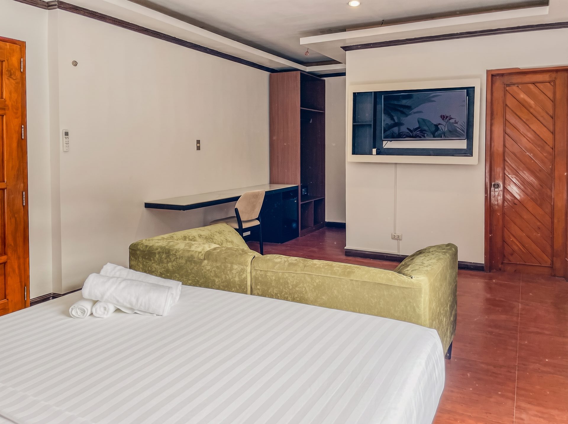Room with green velvet sofa, desk and wooden floors at The Town