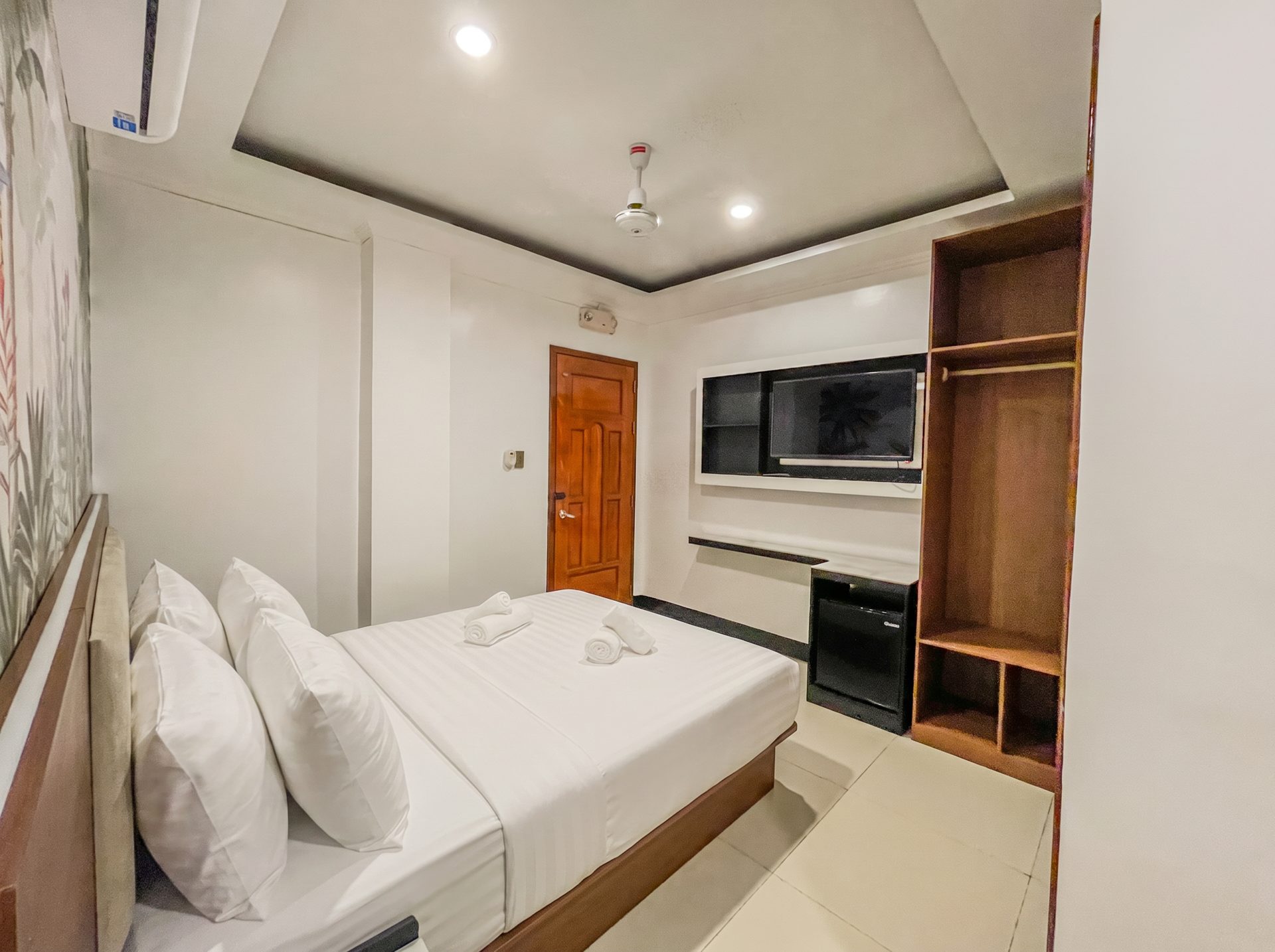 Room with open wardrobe, mini fridge and TV at The Town