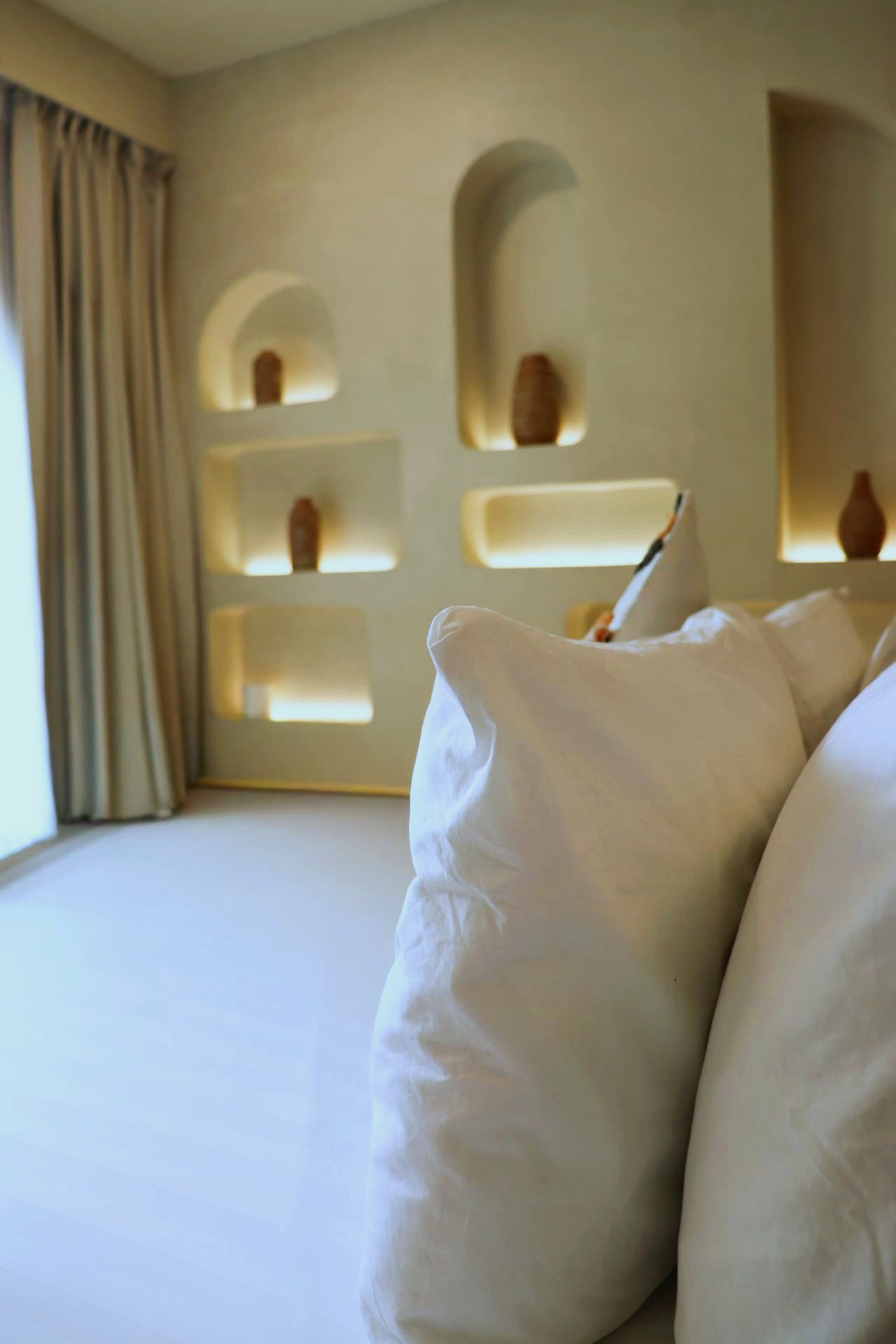Lit plaster niches with ceramic vases beside the bed