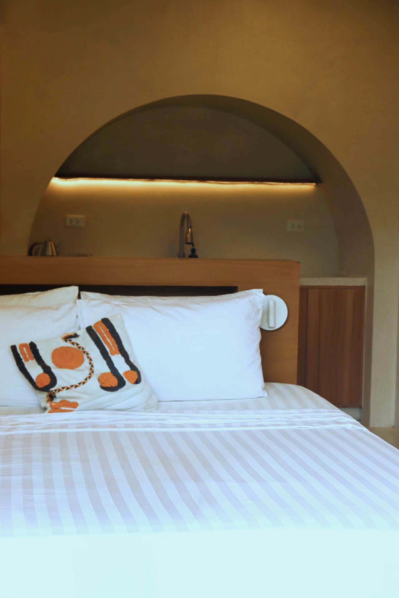 Arched backlit alcove with kettle above the bed headboard