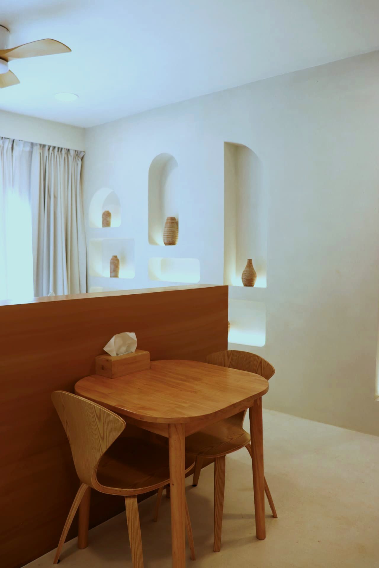 Timber dining table for two beside lit plaster niches