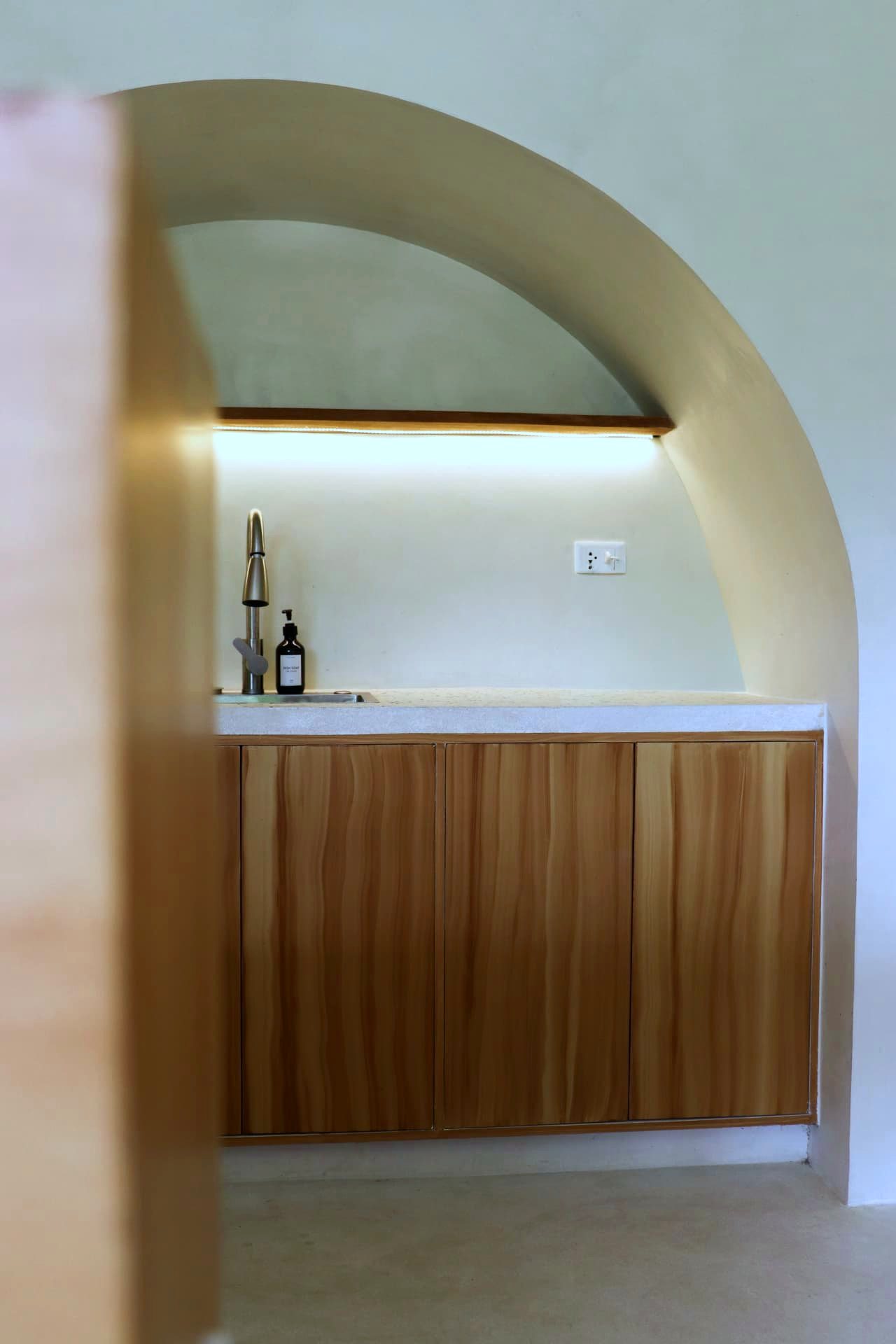 Arched kitchenette with timber cabinetry and terrazzo counter