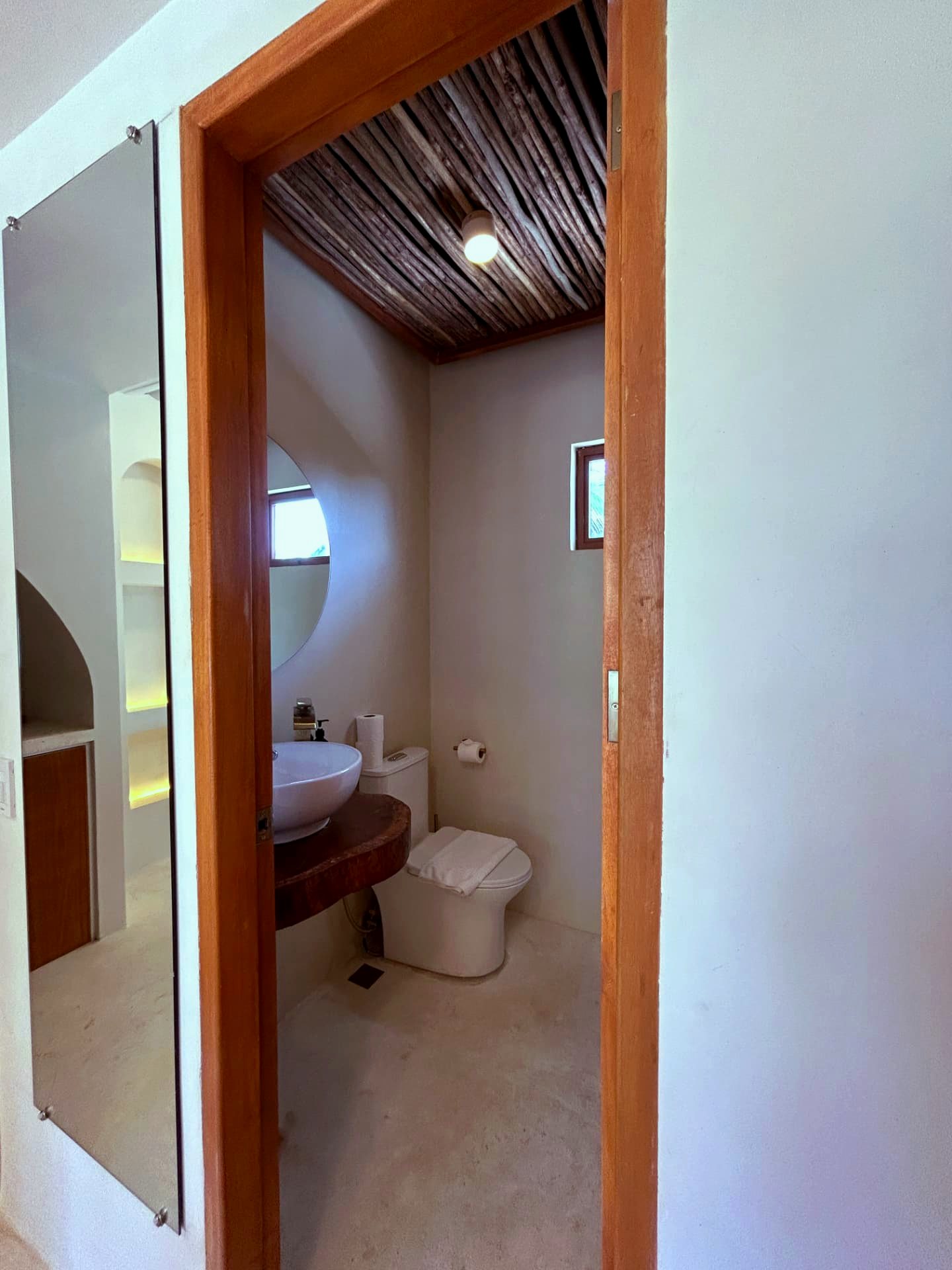 Ensuite bathroom entrance with driftwood ceiling and round mirror