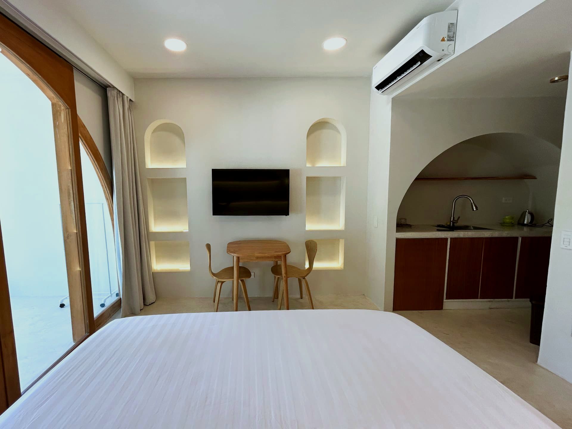 Studio living area with arched niches, dining table and kitchenette