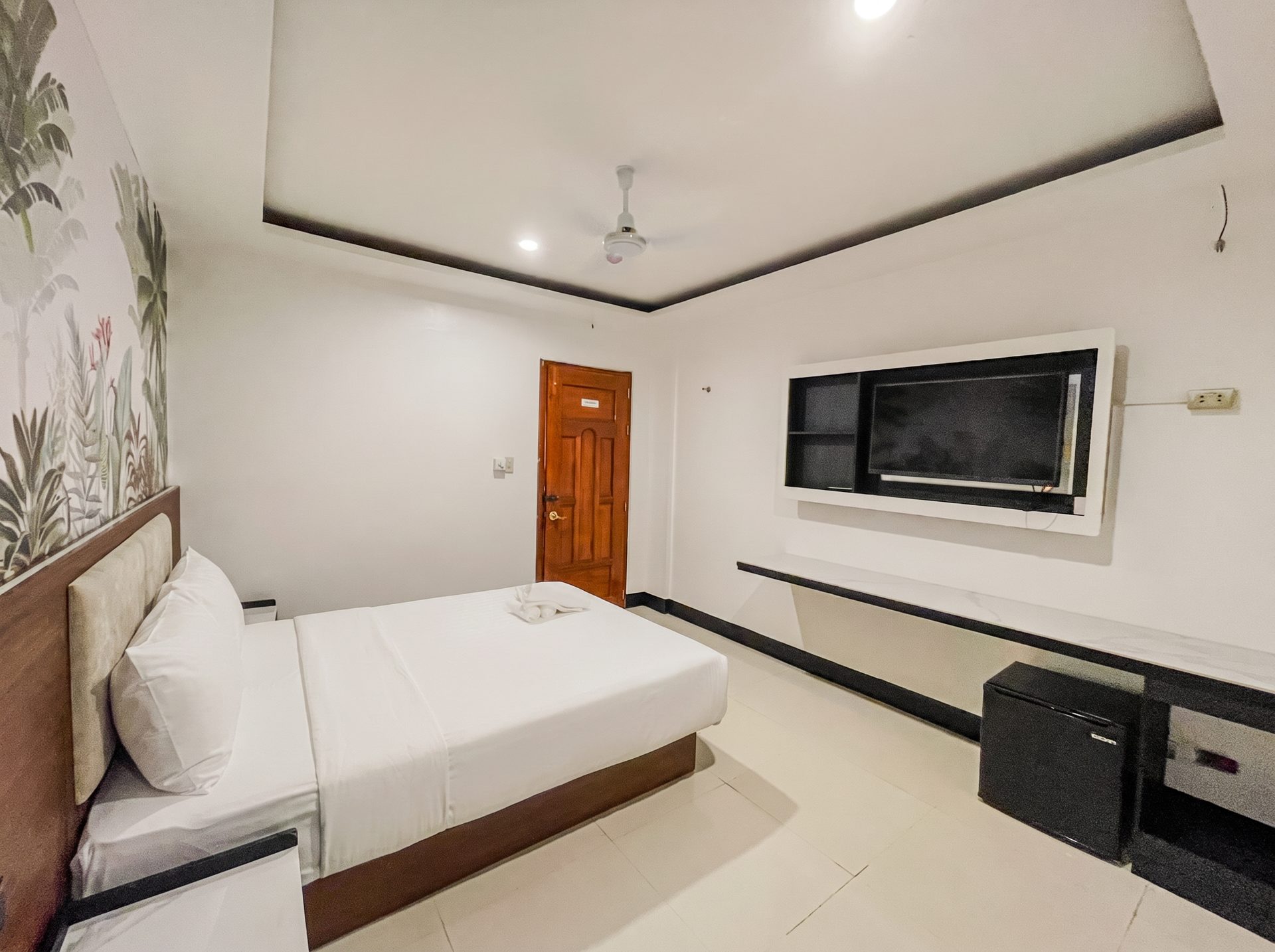 Spacious room with wall-mounted TV and mural at The Town