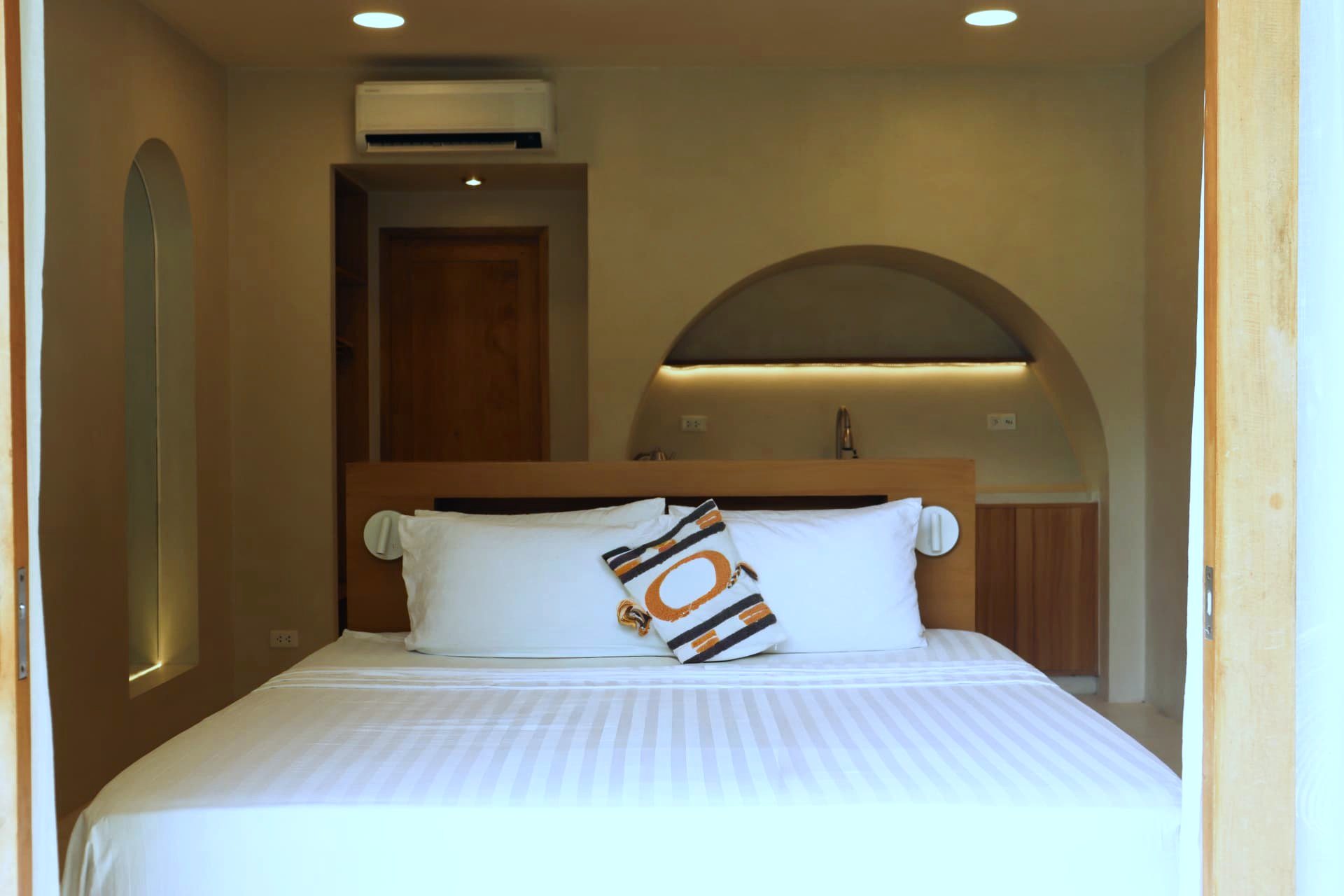 King bed with arched niche and warm lighting in a patio studio