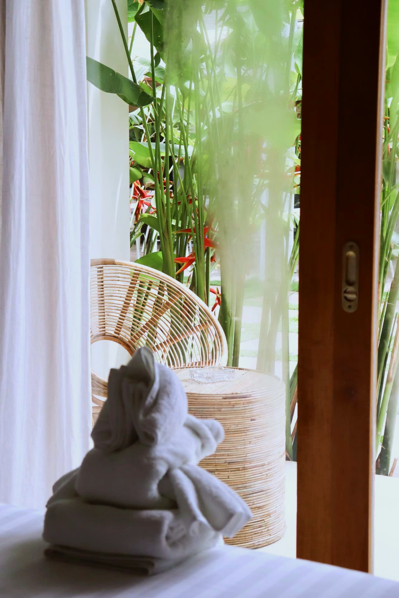 Rattan chair on the patio framed by heliconia and tropical planting